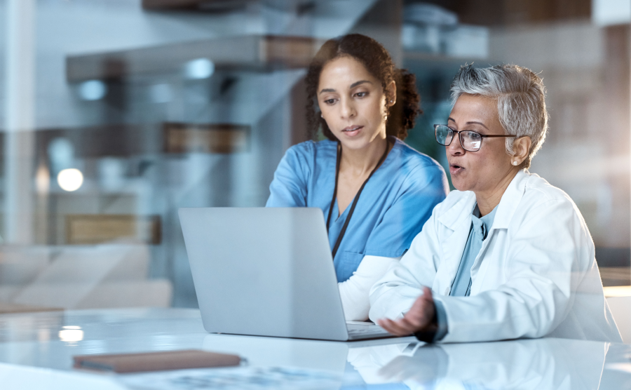 Two women in healthcare looking at a laptop computer