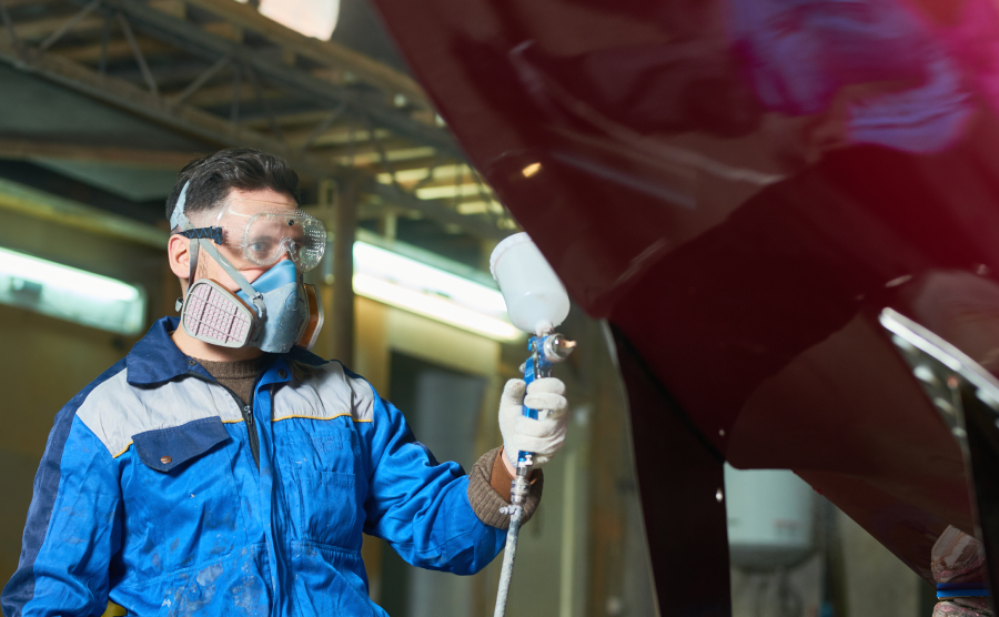 Worker spray painting a ship hull