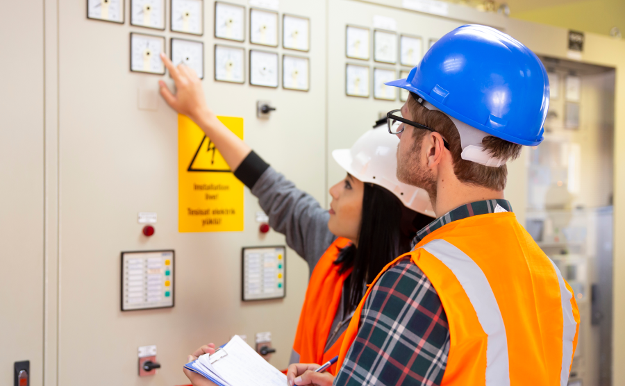 Two workers in hard hats examining equipment in electrical substation